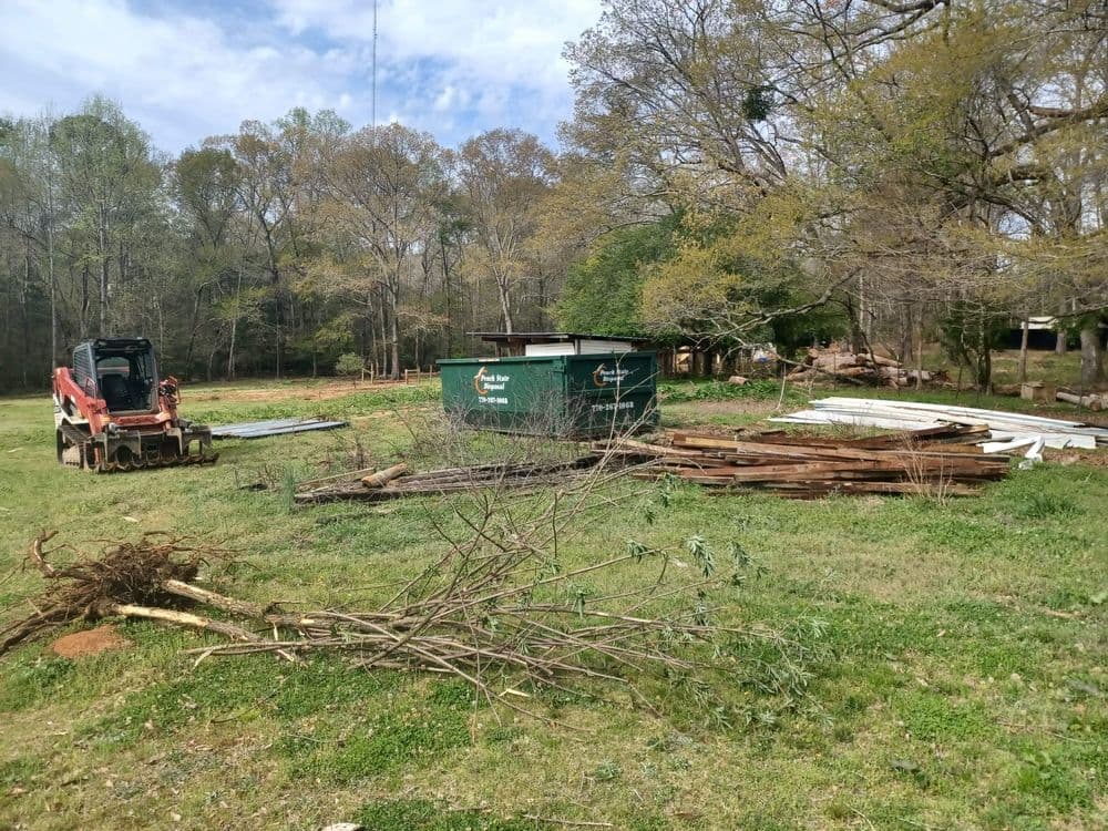 Construction site with a mini excavator, materials, and debris in a rural setting.