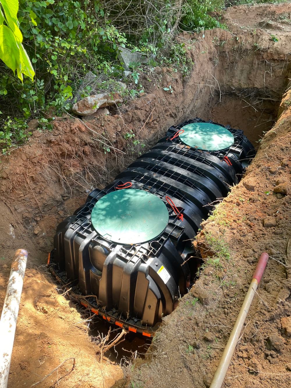 Underground storage system installation in a garden, surrounded by soil and greenery.